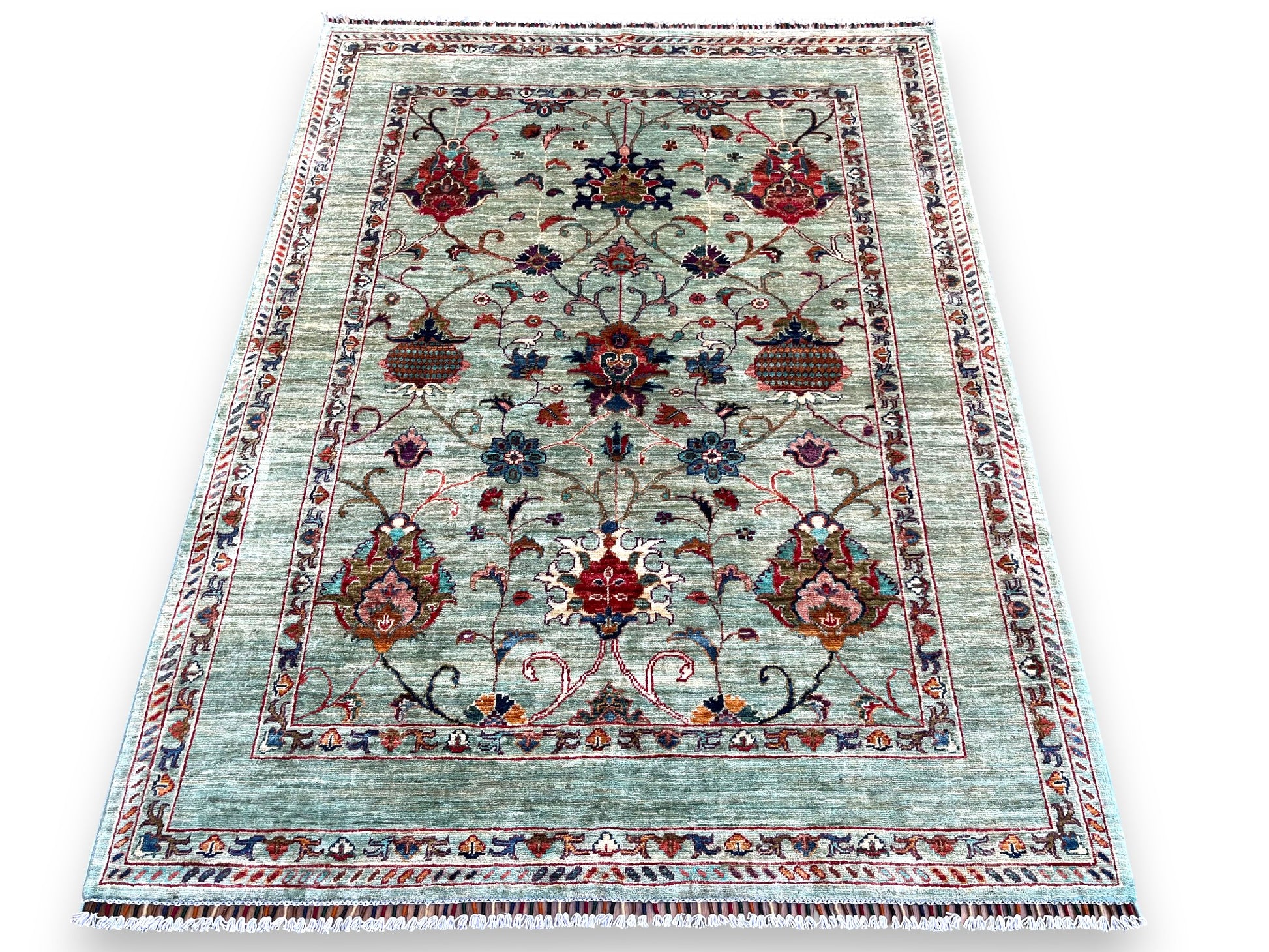 Afghan hand-knotted floral rug styled in elegant living room setting, showcasing how the sage green and burgundy colors complement traditional home decor