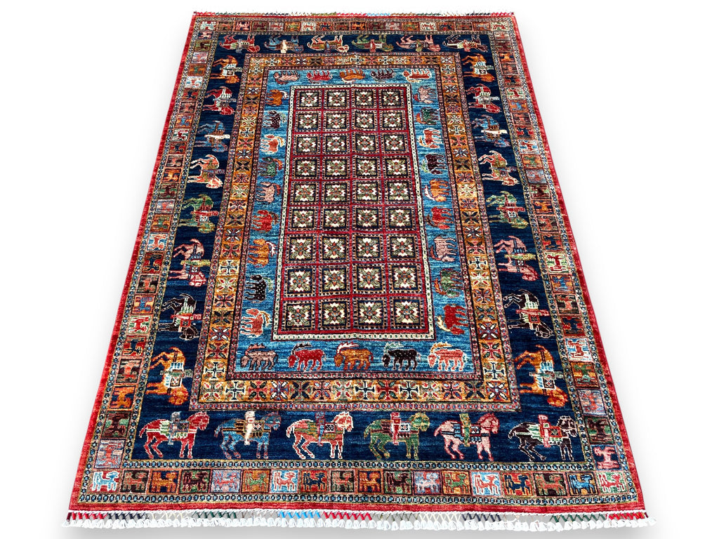 Afghan hand-knotted pictorial rug with burgundy geometric center field, navy borders featuring colorful animals including horses and riders, turquoise accents, and red outer border with white cotton fringe on white background