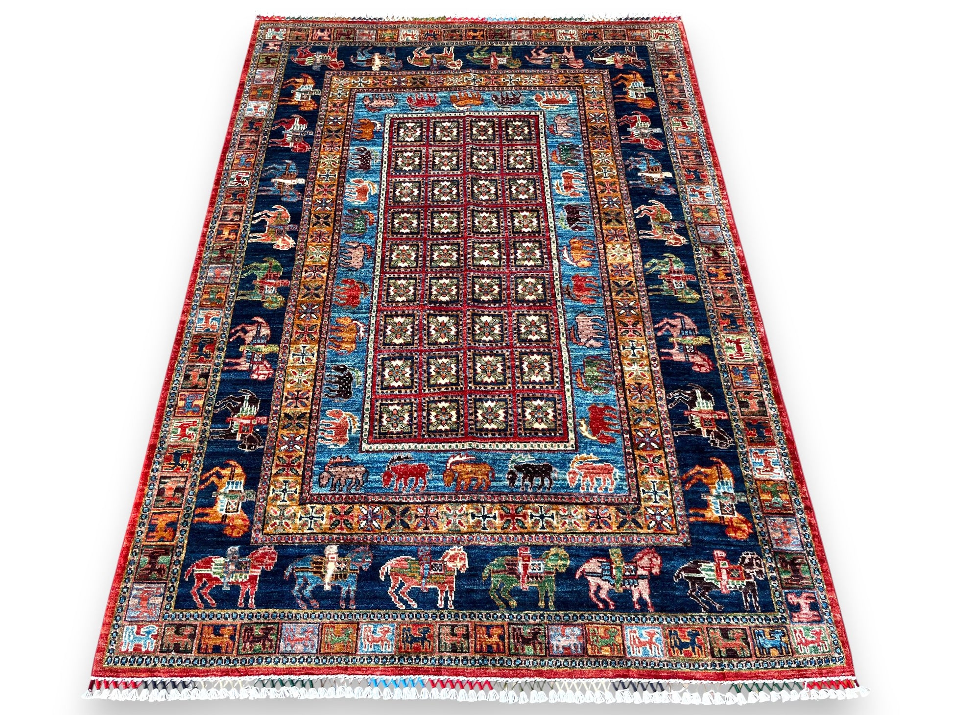 Afghan hand-knotted pictorial rug with burgundy geometric center field, navy borders featuring colorful animals including horses and riders, turquoise accents, and red outer border with white cotton fringe on white background