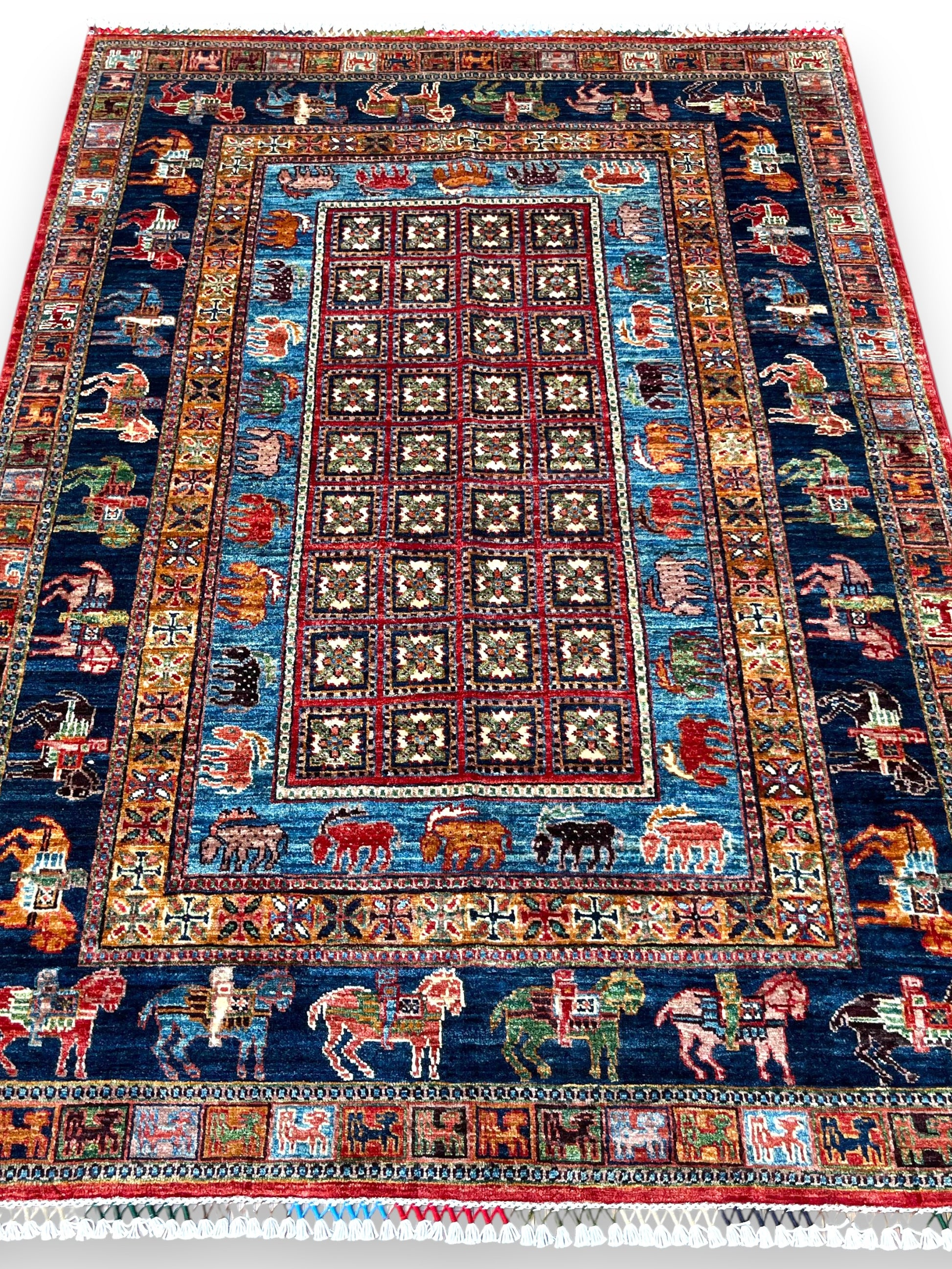 Afghan pictorial hand-knotted rug displayed in elegant room setting showing scale and decorative impact on hardwood floors with furniture arrangement