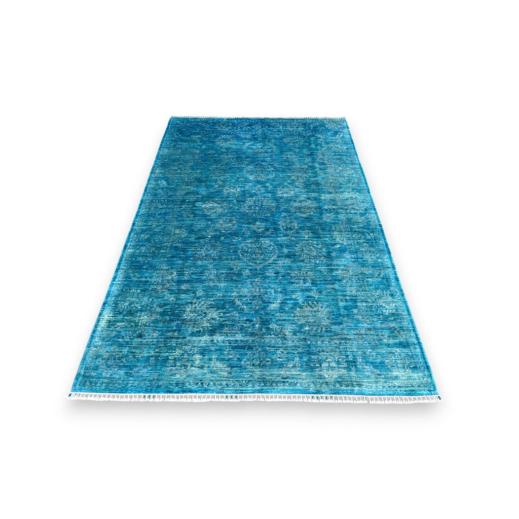 Azure blue overdyed hand-knotted wool area rug 118x80 inches with white cotton fringe, showing watercolor-like color variations and traditional craftsmanship against white background