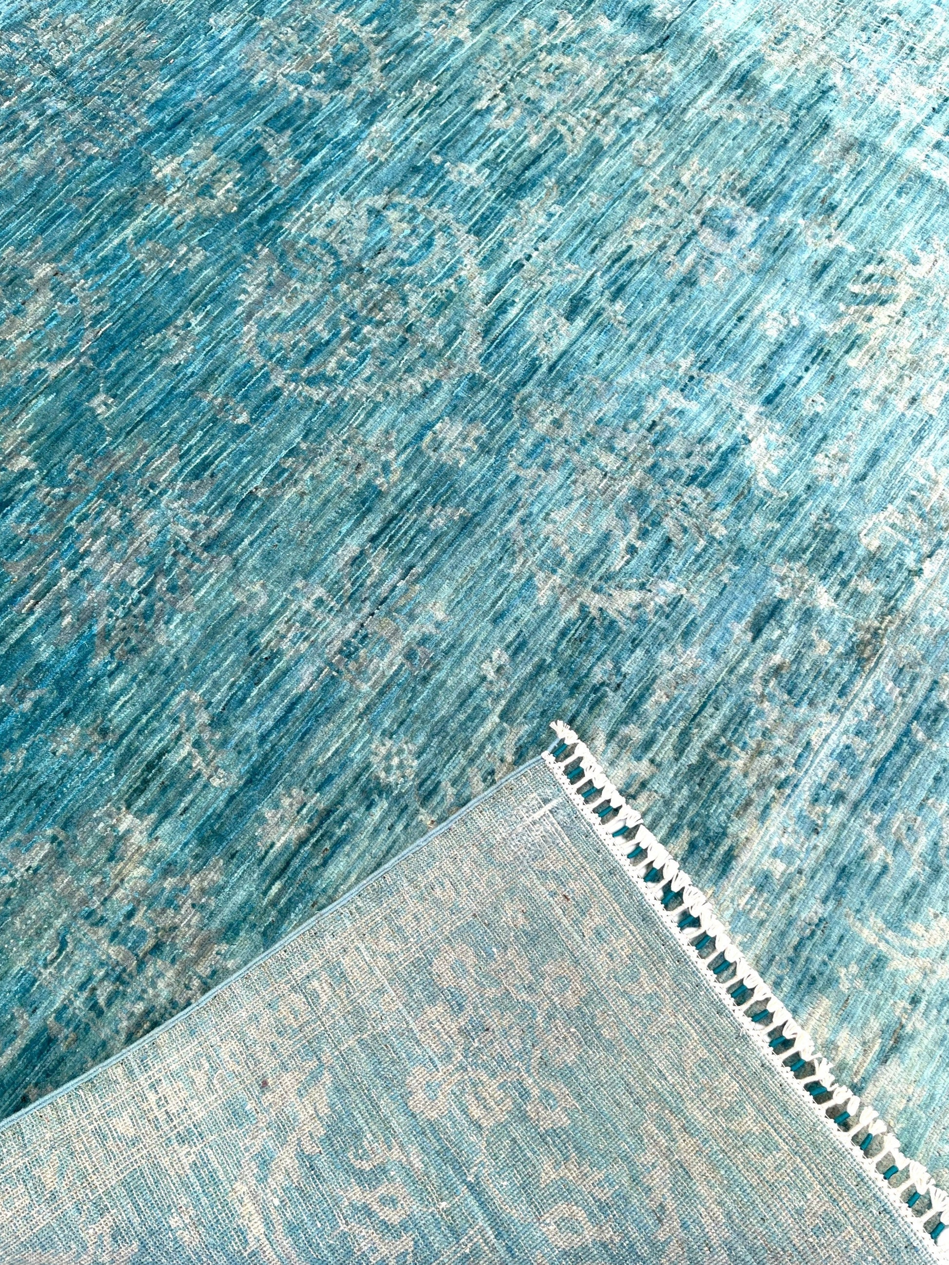 Azure blue overdyed hand-knotted wool area rug 118x80 inches with white cotton fringe, showing watercolor-like color variations and traditional craftsmanship against white background