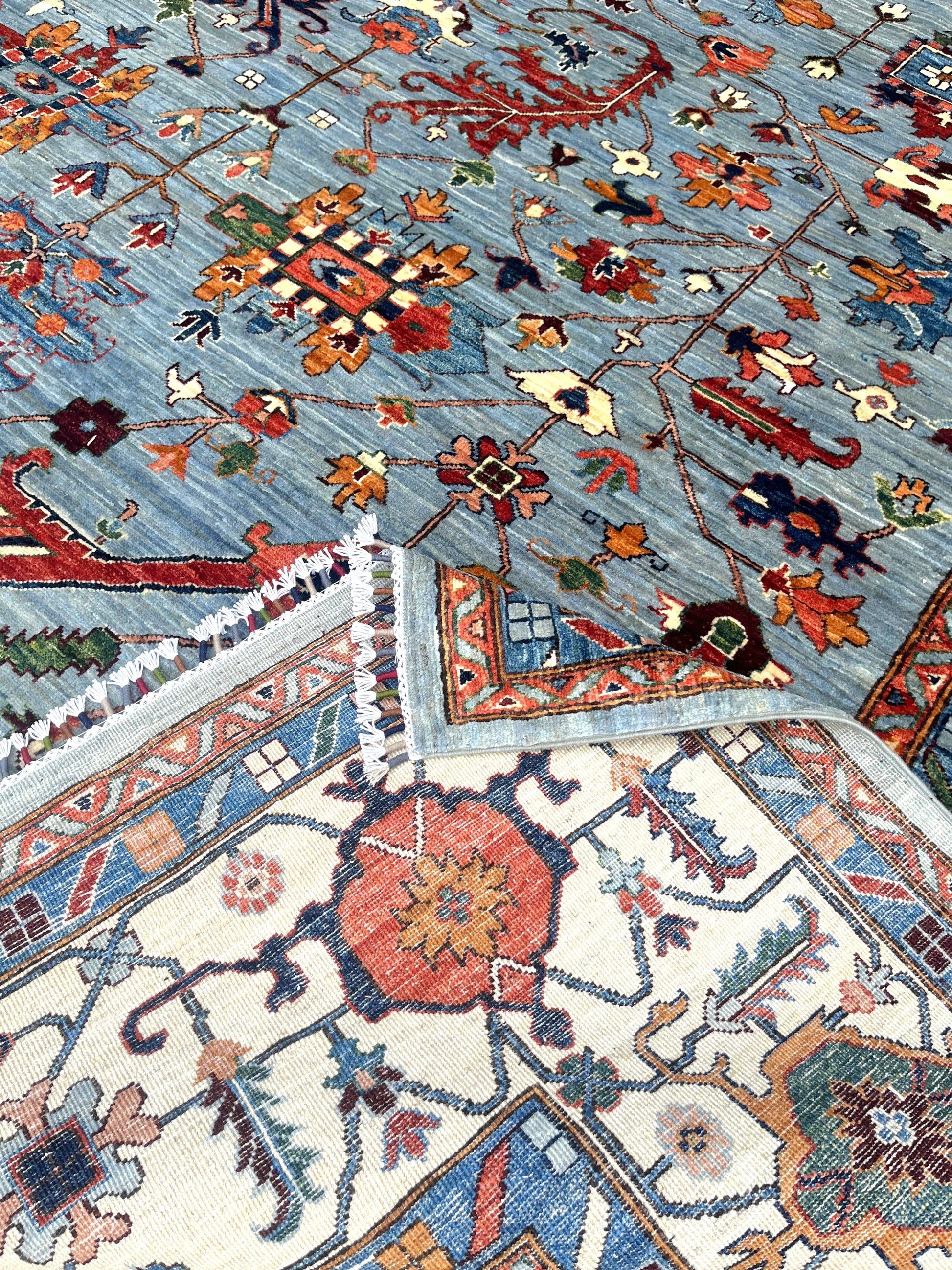 Detailed view of ivory border featuring Afghan palmettes and botanical patterns with premium wool texture