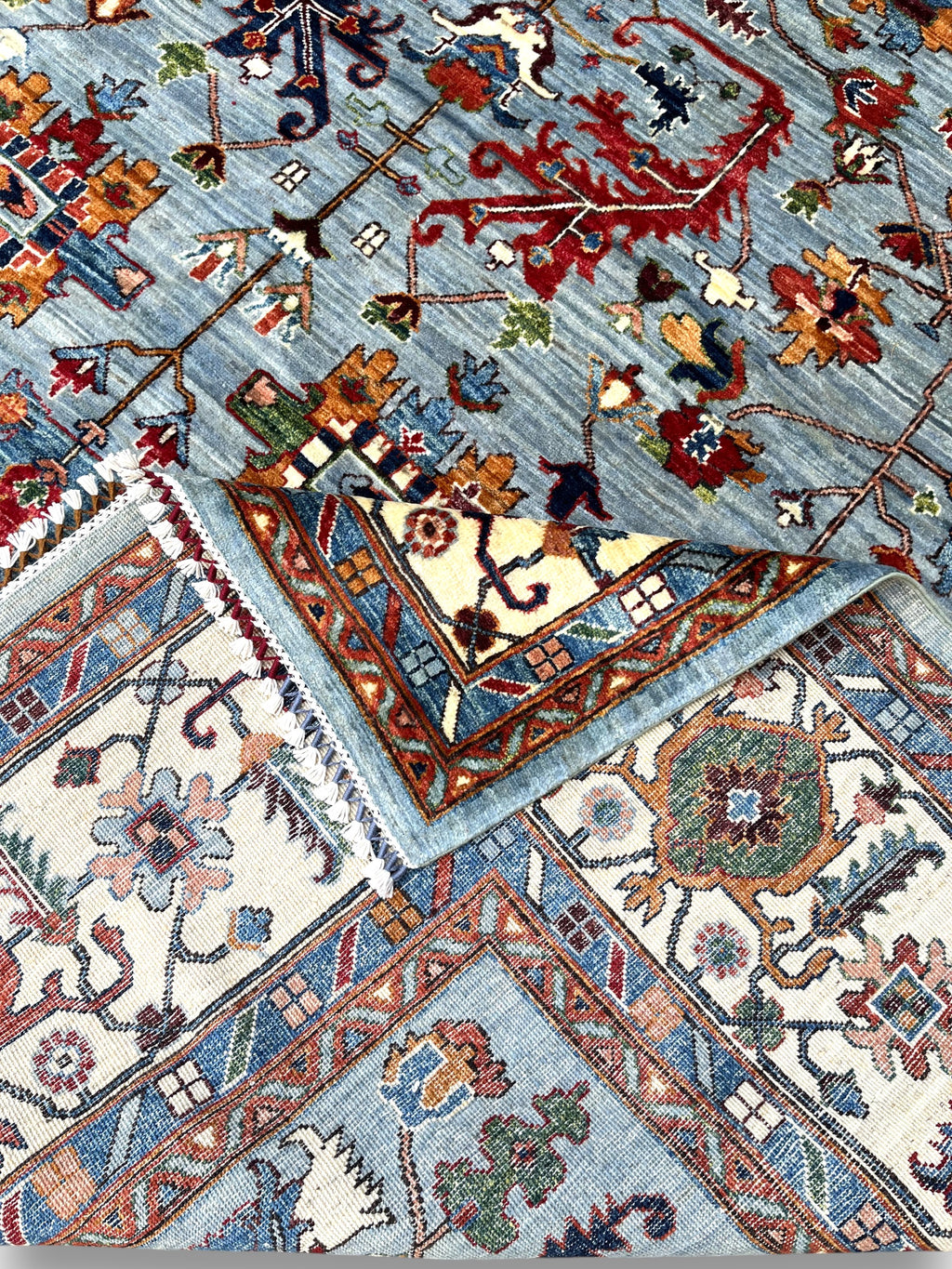 Detailed view of ivory border featuring Afghan palmettes and botanical patterns with premium wool texture