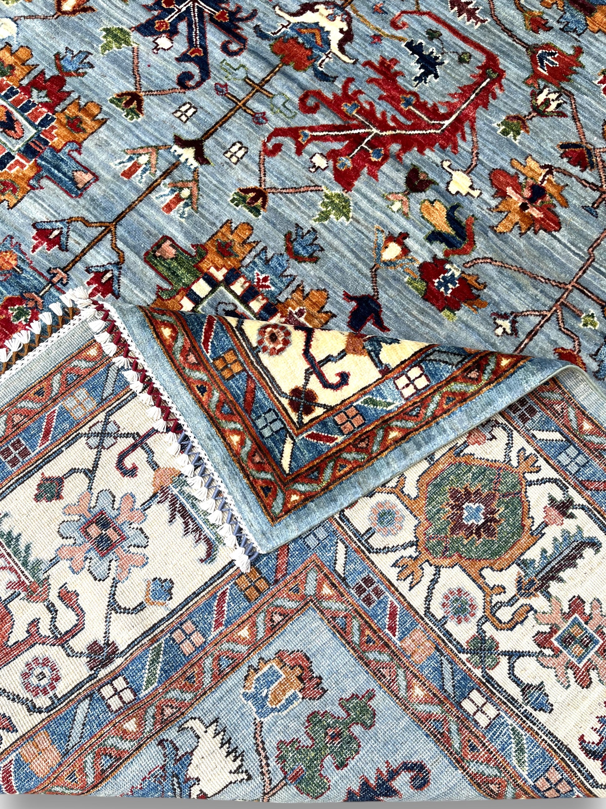 Detailed view of ivory border featuring Afghan palmettes and botanical patterns with premium wool texture
