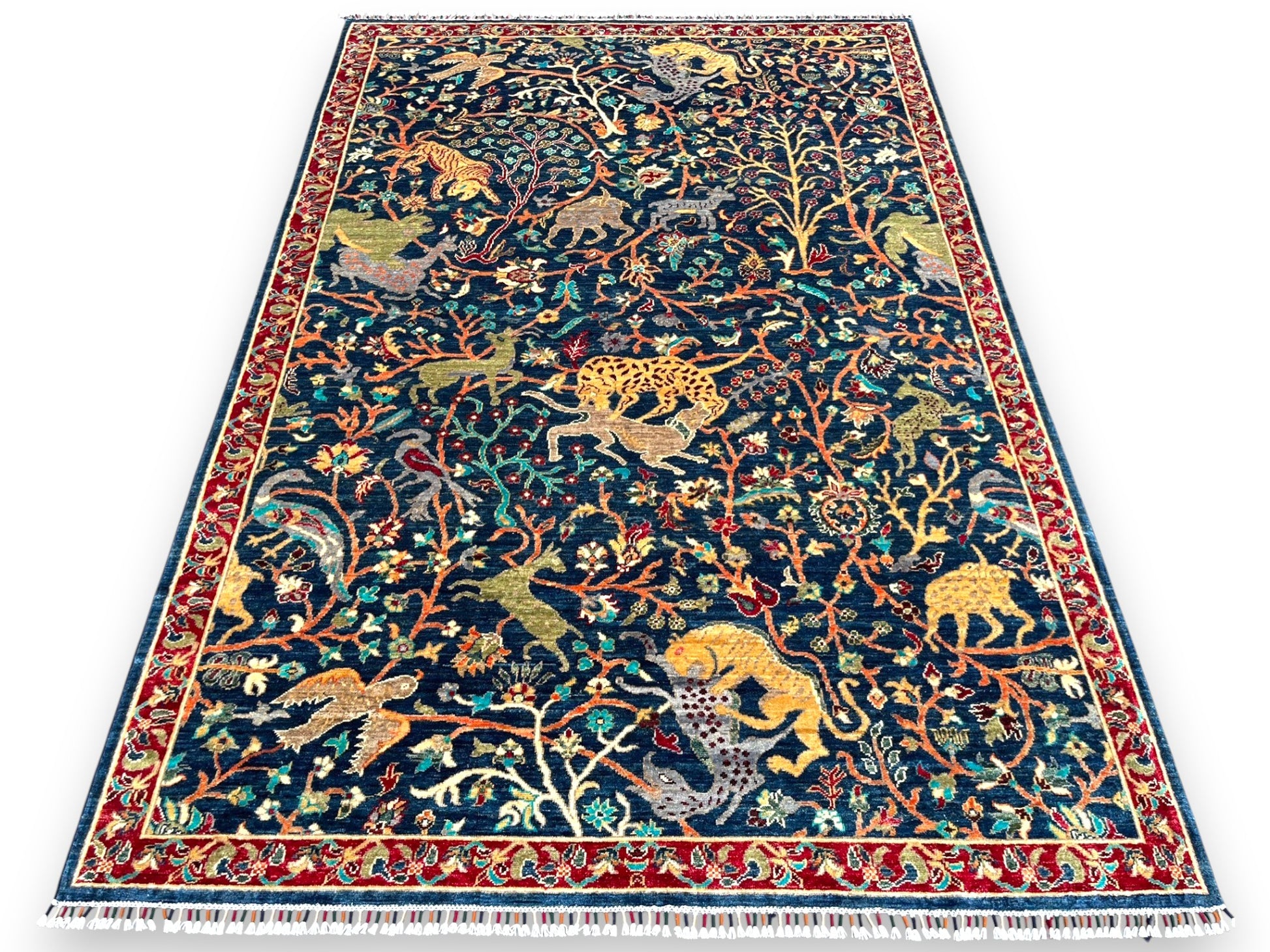 Afghan wildlife hand-knotted rug displayed in elegant living room setting showing scale and decorative impact on hardwood floors